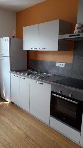 La cuisine est équipée de placards blancs, d'une cuisinière et d'un réfrigérateur. dans l'établissement 13 Rue de Sand, à Matzenheim
