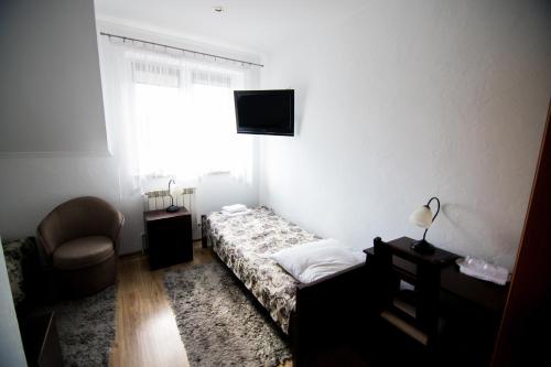 a bedroom with a bed and a chair and a television at Hotel & Spa Arkadia in Tomaszów Lubelski