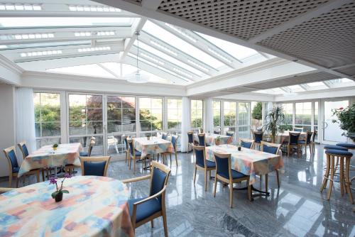 ein Esszimmer mit Tischen und Stühlen und Fenstern in der Unterkunft Hotel Klausenhof Flüeli in Flüeli