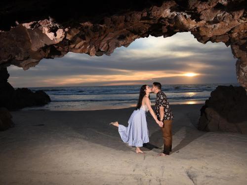 a couple kissing in front of a cave on the beach at Castillos Del Mar in Rosarito