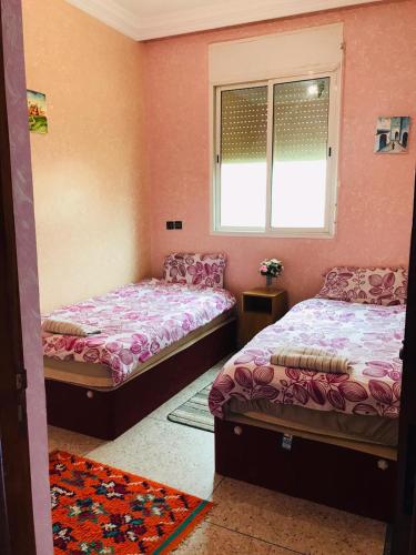 two beds in a room with pink walls at Elmenzah Apartments in Taroudant
