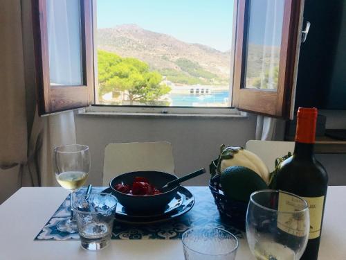 un tavolo con una bottiglia di vino e un cesto di frutta di SOGNO a Favignana