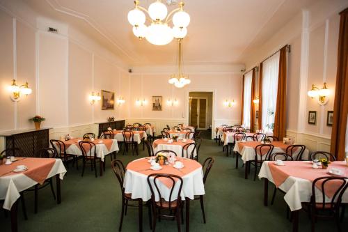 ein Esszimmer mit Tischen, Stühlen und einem Kronleuchter in der Unterkunft Hotel Atlanta in Wien