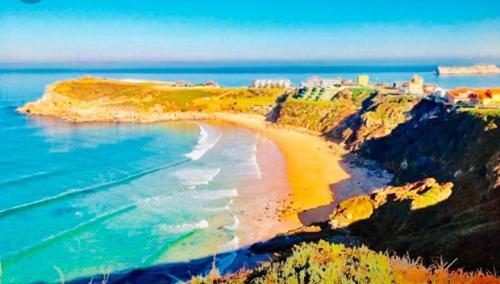 a view of a beach with a town on a cliff at Apartamentos Casa Carmen in Suances