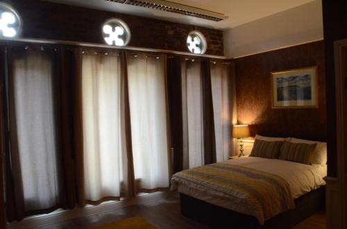 a bedroom with a bed and some windows with curtains at 43A Crown Street in Halifax