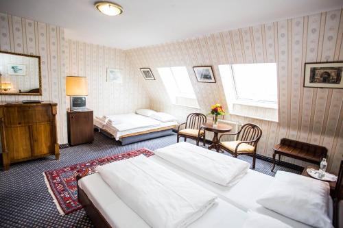 a hotel room with two beds and a table and chairs at Hotel Atlanta in Vienna