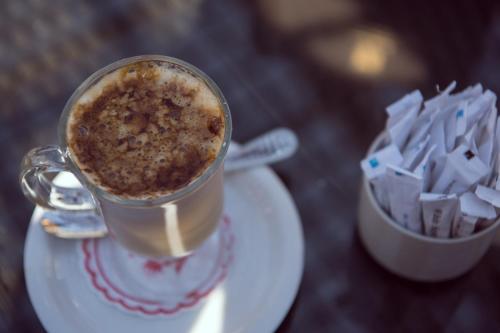 a cup of coffee on a plate next to a cup of sugar cubes at Salma Hotel Cairo in Cairo