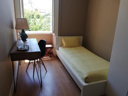 a small bedroom with a bed and a desk and a window at Menina da Ria Guest House in Aveiro
