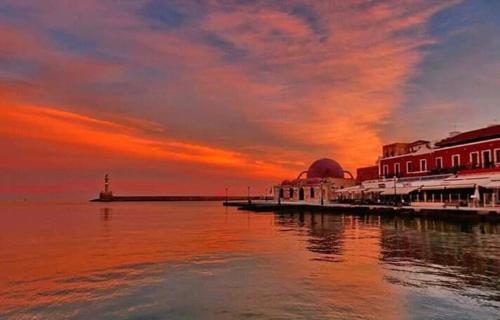 a sunset over a pier with a lighthouse and buildings at Tony Central Luxury Apartment 1 in Chania