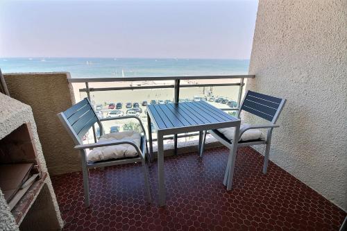 una mesa y 2 sillas en un balcón con vistas a la playa en Studio face à la mer, en Canet-en-Roussillon