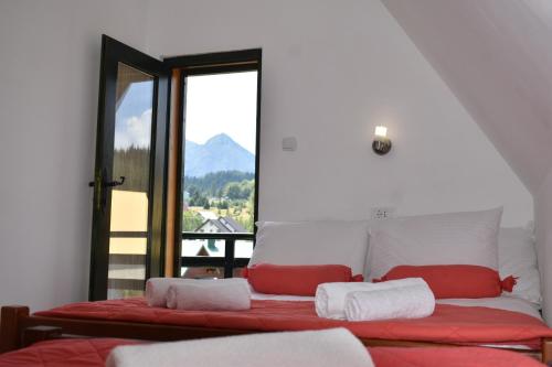 a bedroom with a bed with red and white pillows at Guest house Sky Blue in Žabljak