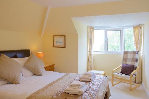 Un dormitorio con una cama y una silla y una ventana. en Little Coombe, en St Ives