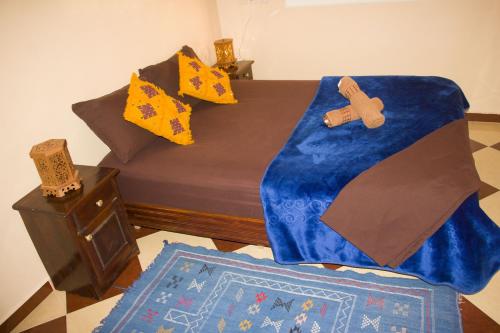 a bed with a blue blanket and crosses on it at GOLVEN Surf in Taghazout