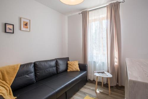 a black leather couch in a living room with a window at The Starlings Apartments Plitvice Lakes in Plitvička Jezera