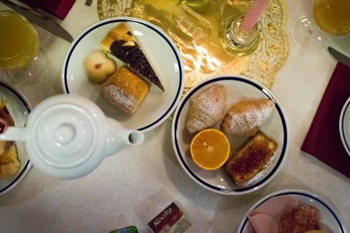 a table with three plates of desserts and a tea pot at Hotel Club Regina E Fassa in Mazzin