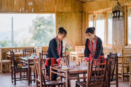 two women sitting at tables in a restaurant at Hoang Su Phi Lodge in Ha Giang