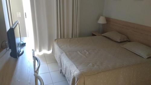 a bedroom with a bed and a lamp and a window at Golden Dolphin Express Roberto imoveis in Caldas Novas