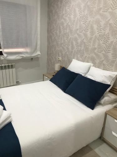 1 dormitorio con 1 cama blanca grande con almohadas azules en O recuncho, pontevedra, en San Salvador de Poio