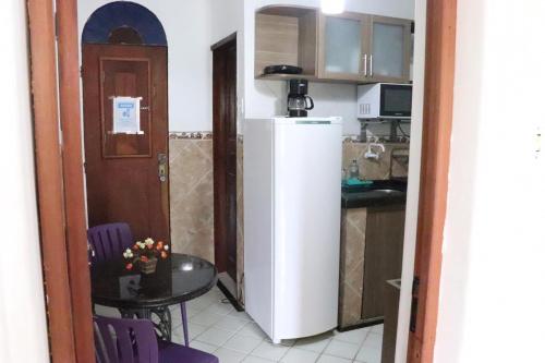 uma cozinha com uma pequena mesa e um frigorífico branco em Casa da Josi - Pajuçara em Maceió