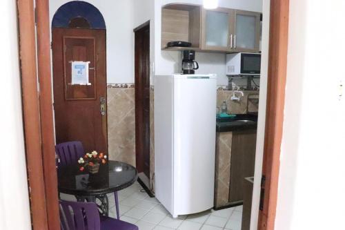 eine Küche mit einem kleinen Tisch und einem weißen Kühlschrank in der Unterkunft Casa da Josi - Pajuçara in Maceió