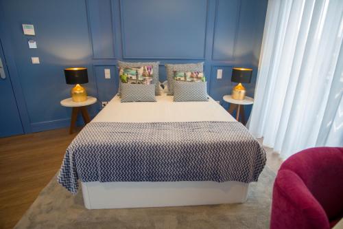 a bedroom with a large bed with blue walls at ZIGZAG HOSTEL in Praia da Vitória