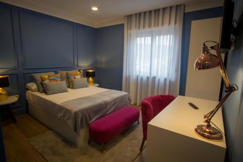 a bedroom with a bed and a table and a chair at ZIGZAG HOSTEL in Praia da Vitória