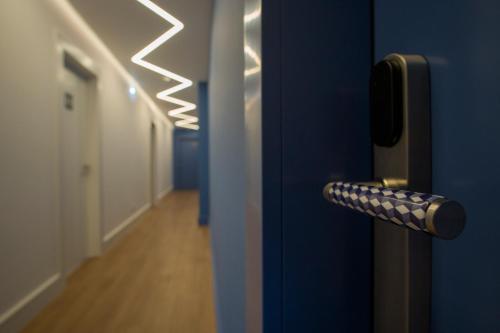 a blue door with a door handle with a hallway at ZIGZAG HOSTEL in Praia da Vitória