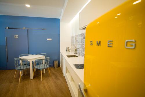 a yellow kitchen with a table and a table and chairs at ZIGZAG HOSTEL in Praia da Vitória