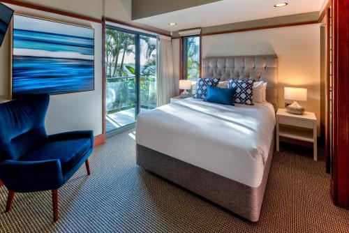 a bedroom with a large bed and a blue chair at Yacht Club Villas on Hamilton Island by HIHA in Hamilton Island