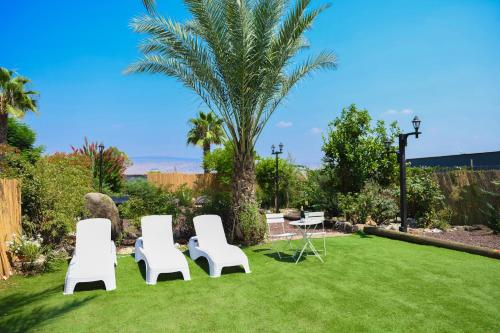 three white chairs and a table and a palm tree at Magical in the Galilee in Qiryat Shemona