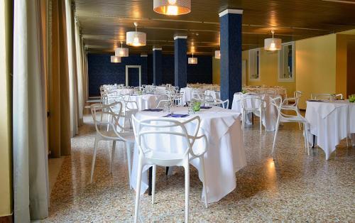 uma sala de jantar com mesas e cadeiras brancas em Hotel Terme di Castel San Pietro em Castel San Pietro Terme