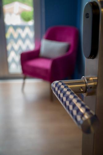 a pink chair and a purple armchair in a room at ZIGZAG HOSTEL in Praia da Vitória