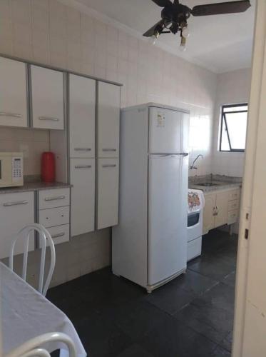 eine Küche mit weißen Schränken und einem weißen Kühlschrank in der Unterkunft praia grande sp in Praia Grande