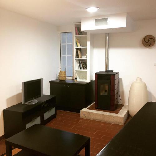 a living room with a tv and a stove at Casa das Catrinas in Ponte da Barca
