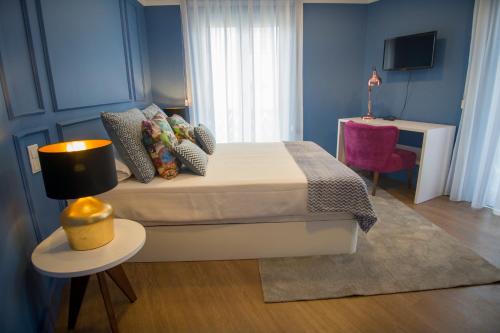 a bedroom with a bed and a table with a lamp at ZIGZAG HOSTEL in Praia da Vitória