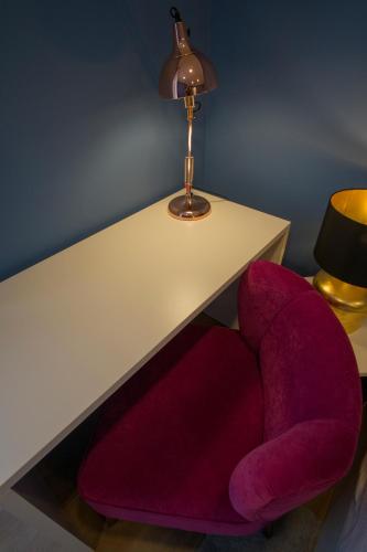a red chair sitting under a table with a lamp at ZIGZAG HOSTEL in Praia da Vitória