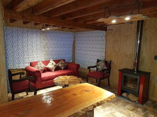 a living room with a red couch and a wood stove at CABAÑAS BOSQUE NEVADO in Malalcahuello