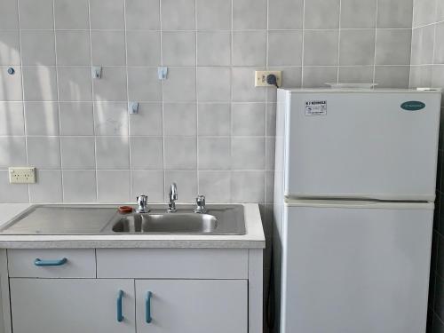 eine Küche mit einer Spüle und einem weißen Kühlschrank in der Unterkunft Lemontree Cottage in Kingscote