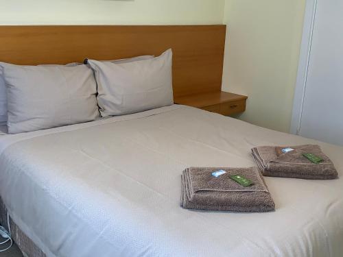 a bed with two towels and two pillows on it at Lemontree Cottage in Kingscote