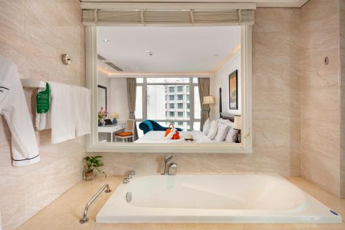 a bath tub in a bathroom with a large mirror at Alagon D'antique Hotel & Spa in Ho Chi Minh City
