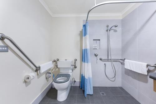 a bathroom with a toilet and a shower at Quest Tamworth in Tamworth