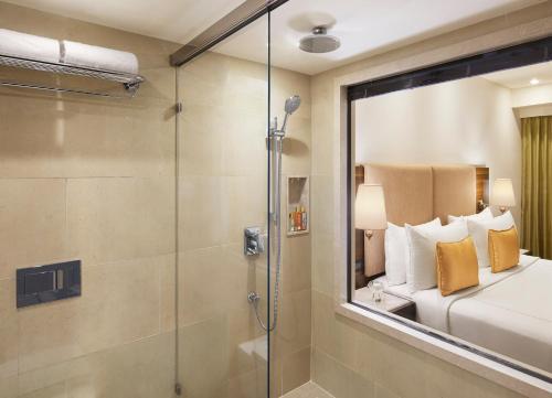 a bathroom with a shower and a bed and a glass shower stall at President - IHCL SeleQtions in Mumbai