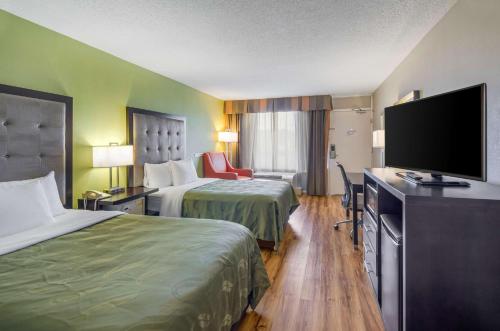 a hotel room with two beds and a flat screen tv at Quality Inn Roanoke Airport in Roanoke