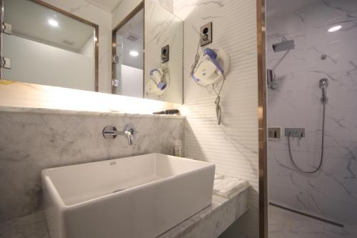 a white bathroom with a sink and a shower at Bestie Hotel in Busan