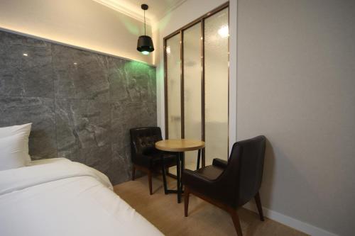 a bedroom with a bed and a table and chairs at Bestie Hotel in Busan