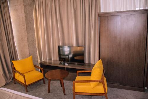 a room with a desk and two chairs and a television at Hotel Nobilis Hall in K'obulet'i