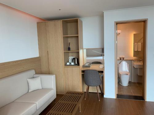 een woonkamer met een witte bank en een badkamer bij Lemain Hotel in Jeju-stad