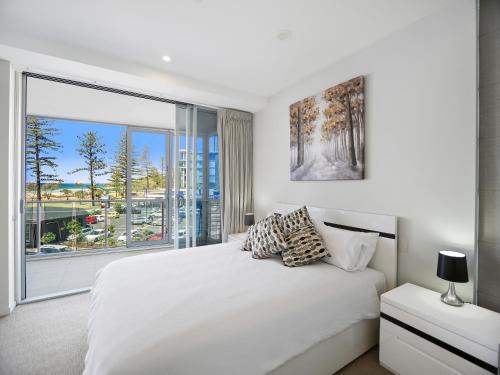 a bedroom with a white bed and a large window at Nirvana By The Sea in Gold Coast