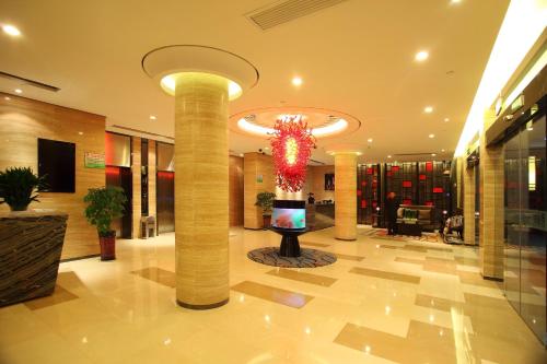 un vestíbulo con columnas y una lámpara de araña en un edificio en Yiwu Bai Heng Hotel, en Yiwu