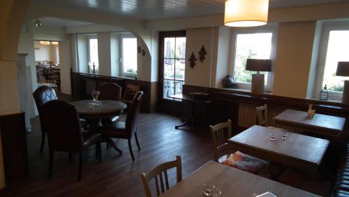 a restaurant with tables and chairs and windows at Hotel Café del Maar in Schalkenmehren